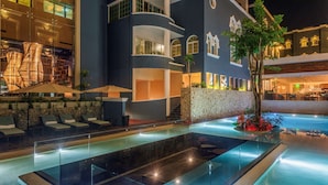 A modern hotel with a pool area, outdoor seating, and a stone wall. - Villa Mercedes Merida, Curio Collection by Hilton (Mérida)