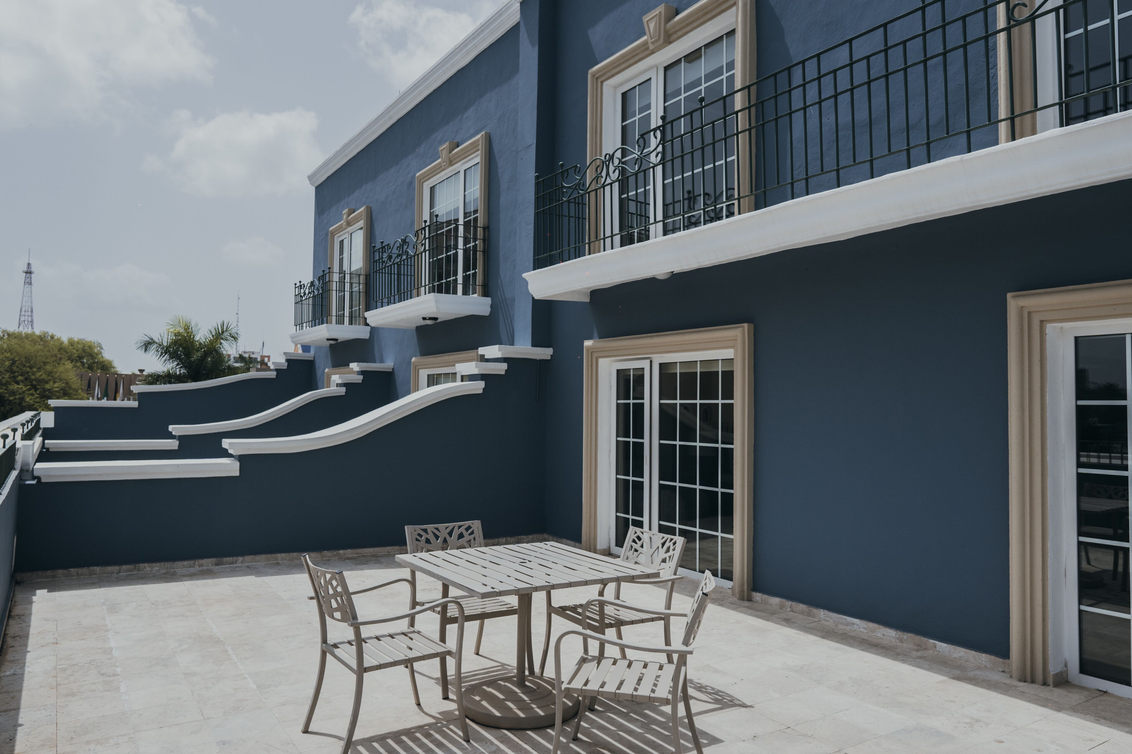 A building with a blue exterior, white trim, and a balcony with metal railings.