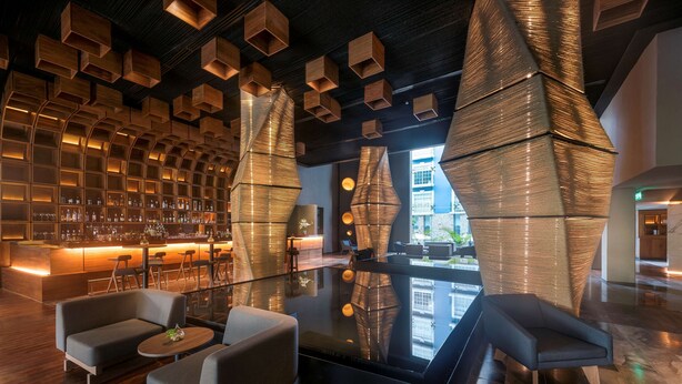 A modern bar area with a wooden wall, seating, and a reflective floor. - Villa Mercedes Merida, Curio Collection by Hilton (Mérida)