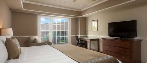 Habitación de hotel con una cama grande, un escritorio, un televisor y ventana con vistas al exterior.