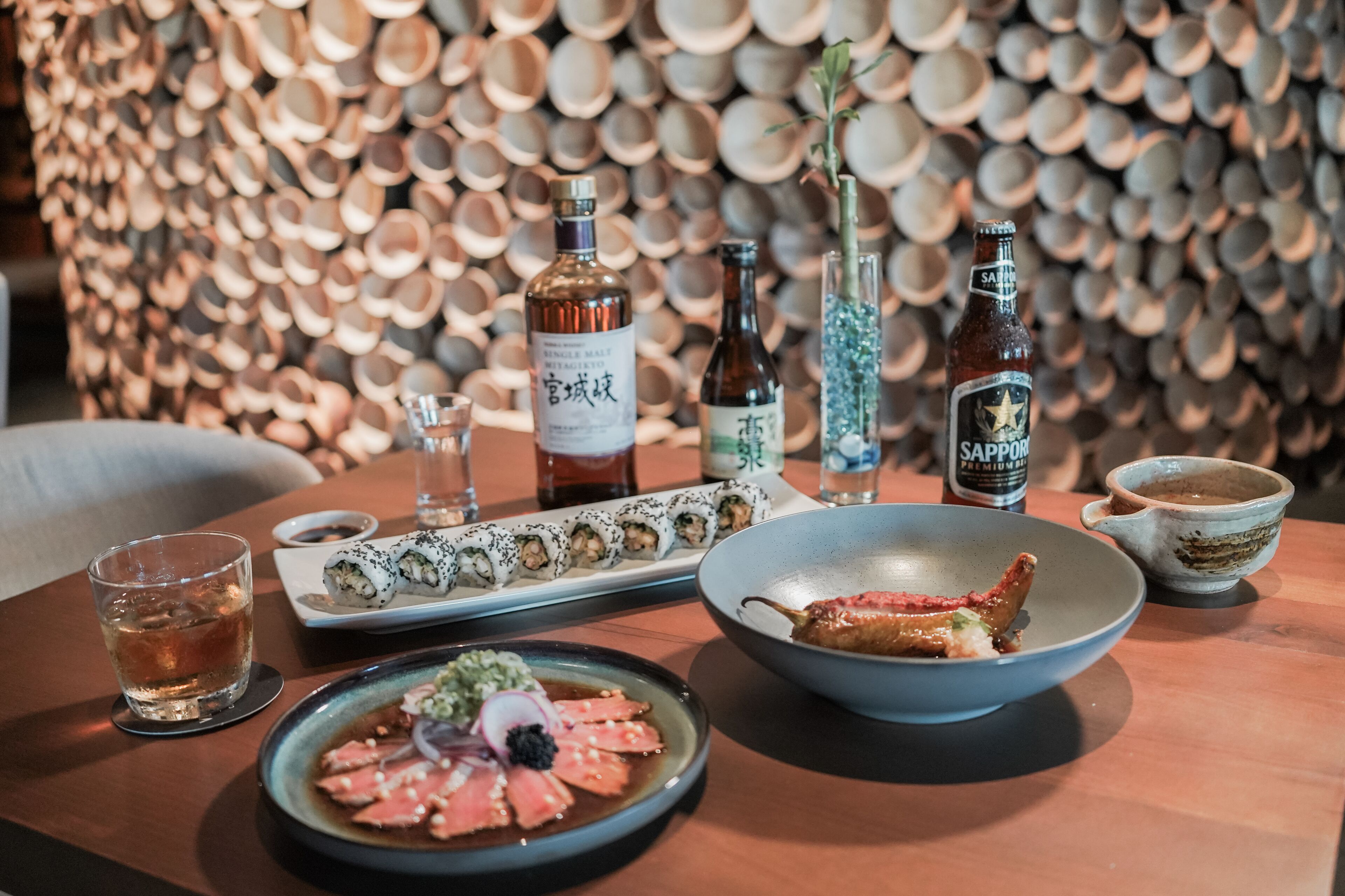 A dining table with sushi, sashimi, and sake bottles.