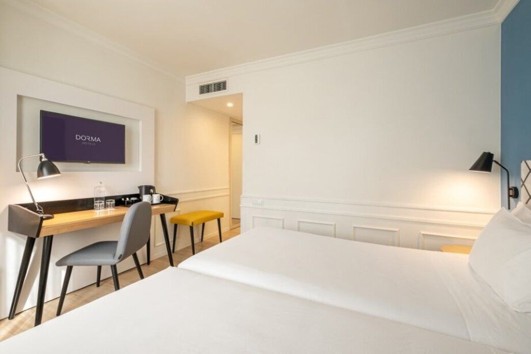 Une chambre d’hôtel comprenant un lit, un bureau avec une chaise, une télévision et une lampe.