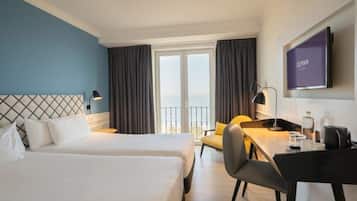 A hotel room with two beds, a desk, a chair, a TV, and a balcony with curtains.