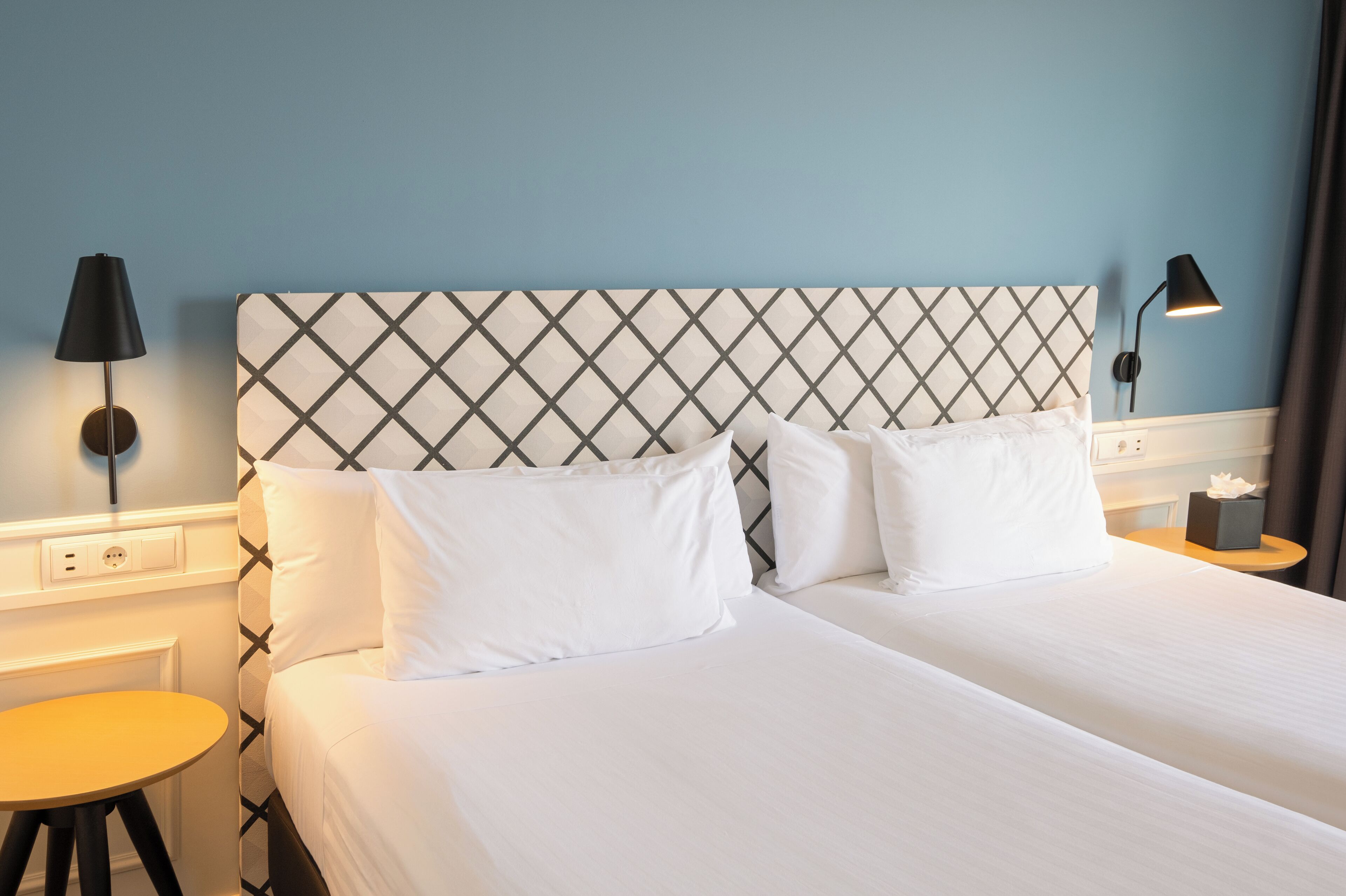 A hotel room with a large bed, two bedside tables, and a nightstand with a lamp.