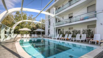 Een buitenzwembad, parasols bij het zwembad en ligstoelen