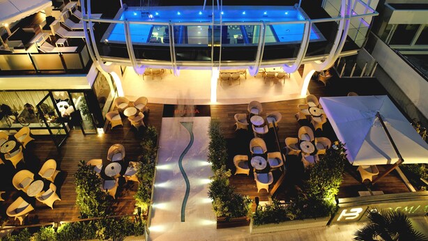 Un bar en la azotea con piscina, rodeado de asientos al aire libre y sombrillas.