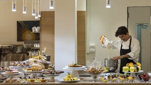 Montaje de bufé con diversas opciones de comida y un chef sirviendo un líquido.