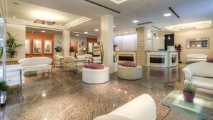 Un moderno vestíbulo de hotel con piso de granito pulido, sofás blancos y una mesa de centro.