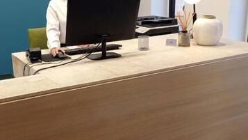 A reception desk with a computer, a lamp, and a vase.