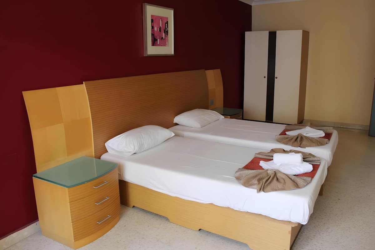Una habitación de hotel con una cama doble, una mesita de noche, un armario y un cuadro en la pared.