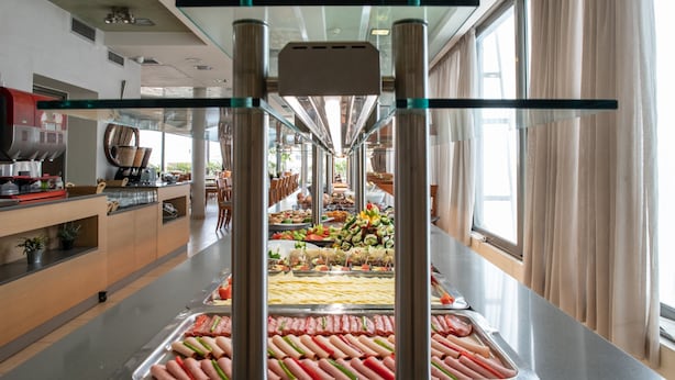 A buffet area with various food options and a kitchen in the background. - Golden City Hotel (Athens)