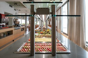 Ett område med en buffé där det finns olika sorters mat, och ett kök syns i bakgrunden.