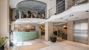 A spacious lobby with a reception desk, seating area, and an elevator. - Golden City Hotel (Athens)