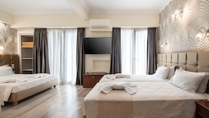 A hotel room with two beds, a flat-screen TV, an air conditioning unit, a wooden nightstand, and a decorative wall panel. - Golden City Hotel (Athens)