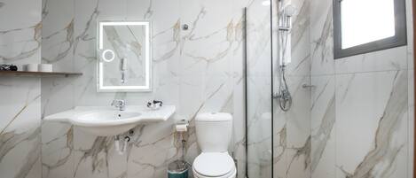 Um banheiro com parede de mármore, pia, vaso sanitário e chuveiro.