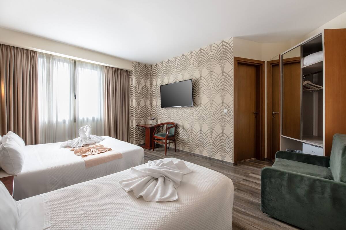 Hotellihuone, jossa on kaksi sänkyä, televisio, työpöytä ja vaatekaappi.