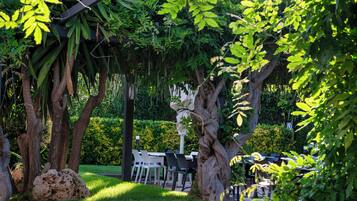 Un jardín al aire libre con un pérgola, asientos y una mesa de comedor.