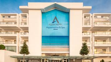 A modern hotel with a prominent Aqua Hotel Aquamarina & Spa sign, multiple balconies, and a glass entrance.