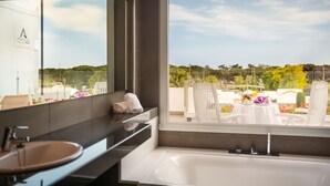 A modern bathroom with a large window, a sink, and a bathtub. - AQUA Hotel Aquamarina & Spa (Santa Susanna)