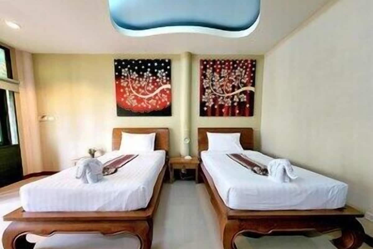A hotel room with two single beds, a flat-screen TV, and artwork on the walls.