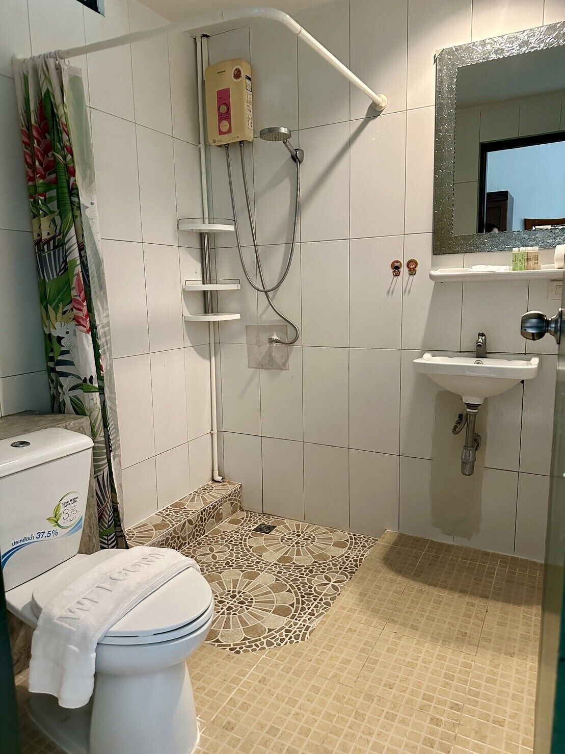 A bathroom with a shower, toilet, sink, and decorative shower curtain.