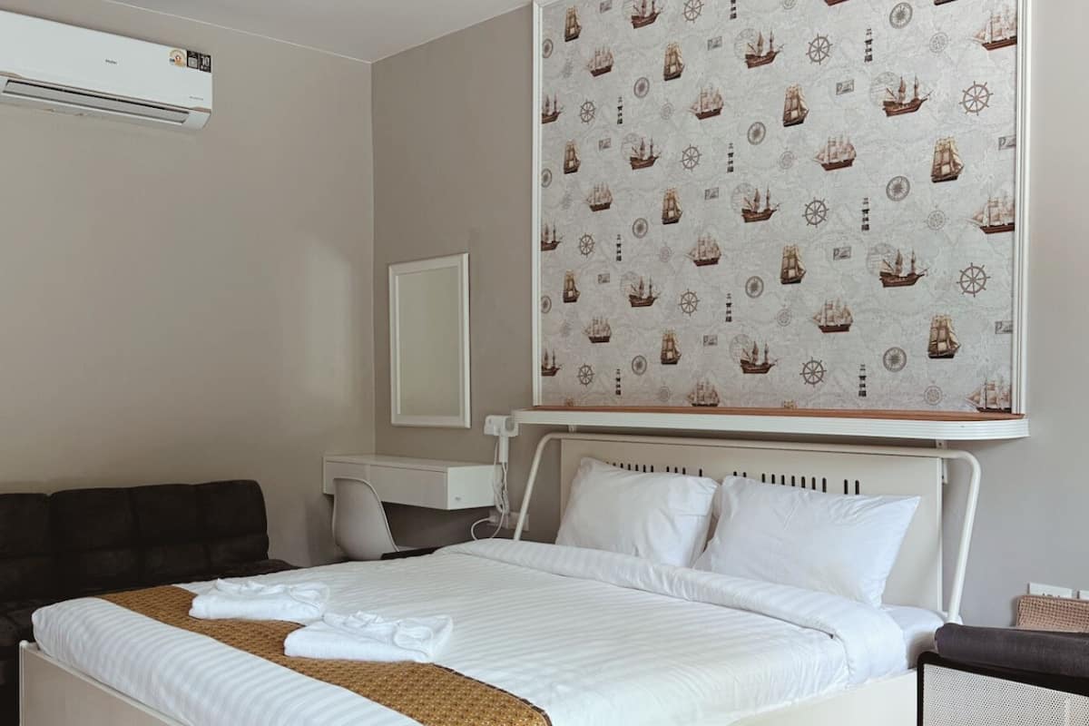A modern bedroom with a bed, bedside tables, a desk, and a ceiling light.