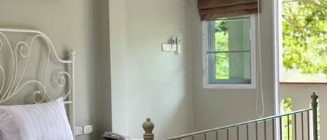 Un dormitorio con cama, mesita de noche, ventana con vistas y un cuadro decorativo en la pared.