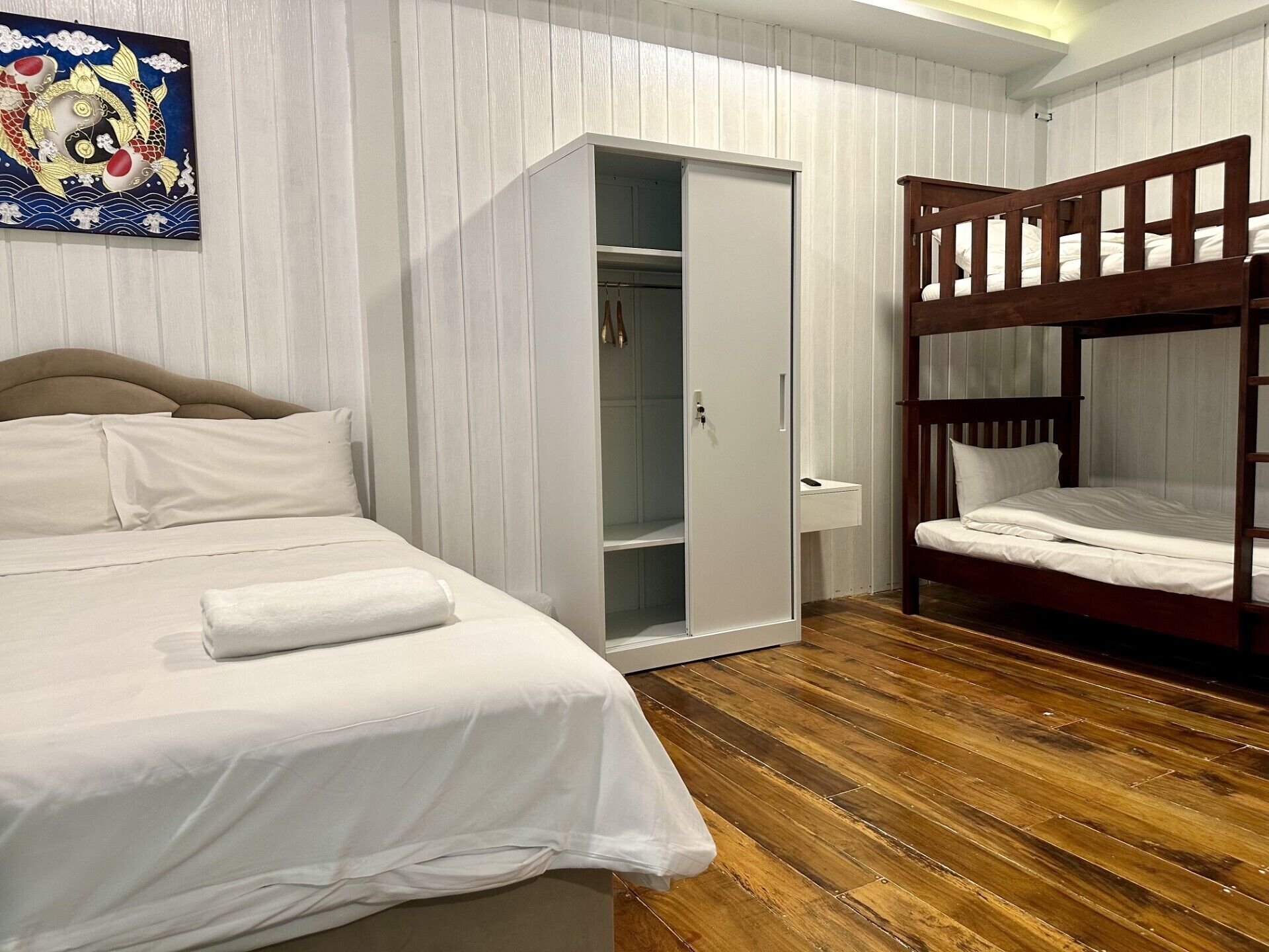 A bedroom with a bunk bed, a wardrobe, and a painting on the wall.
