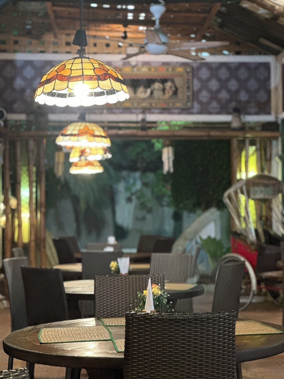 Un comedor interior con mobiliario de mimbre y lámparas colgantes.