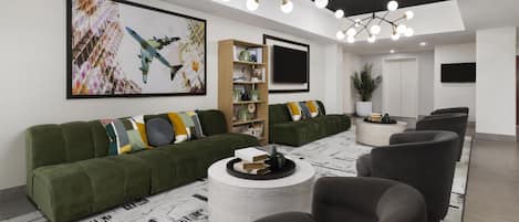 A modern living room with a green sofa, a round coffee table, and a large painting on the wall.