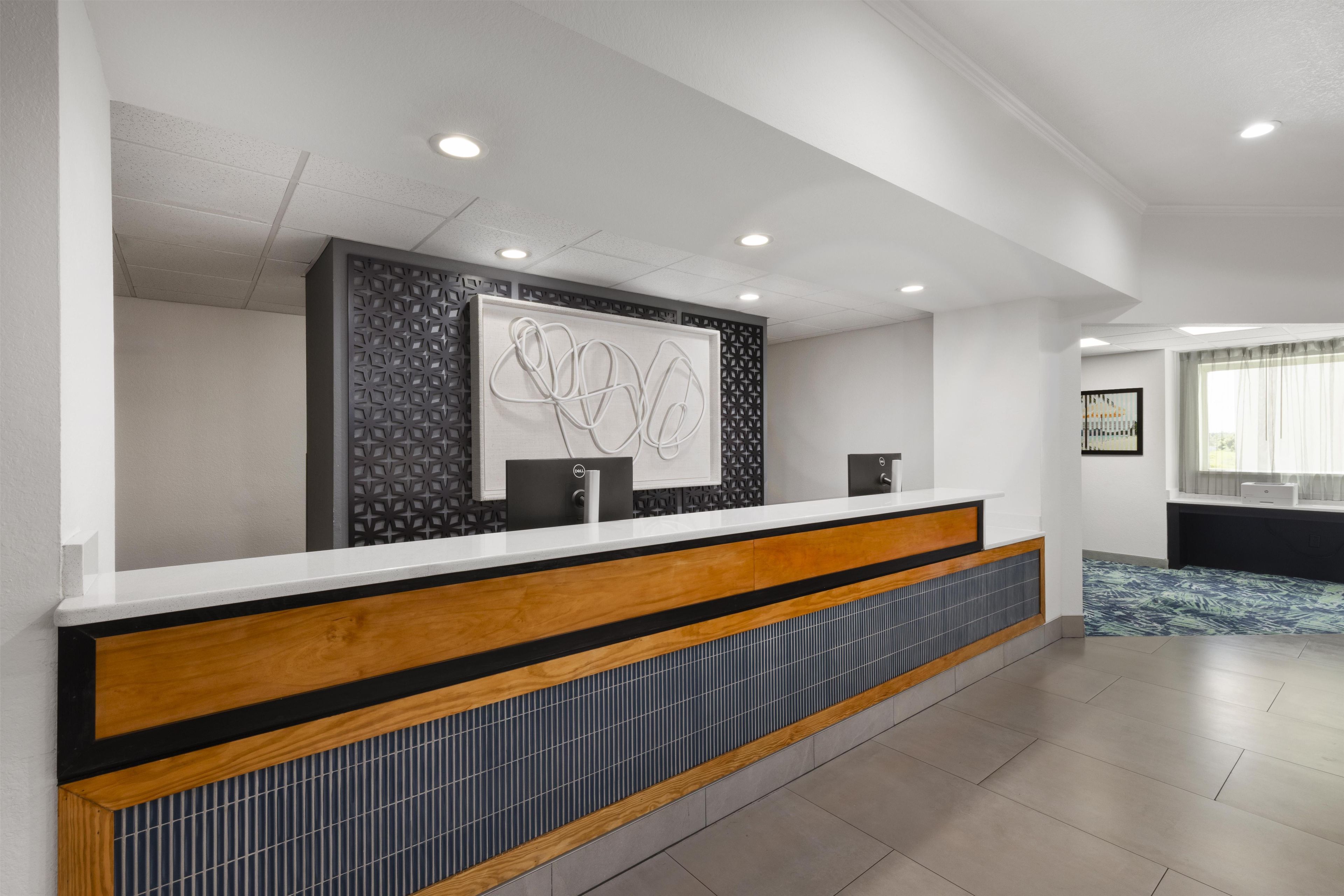 A reception desk with a modern design, a patterned wall, and a large window with curtains.