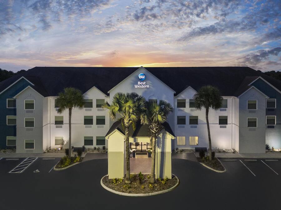 A Best Western hotel with a parking lot and a landscaped area with palm trees.