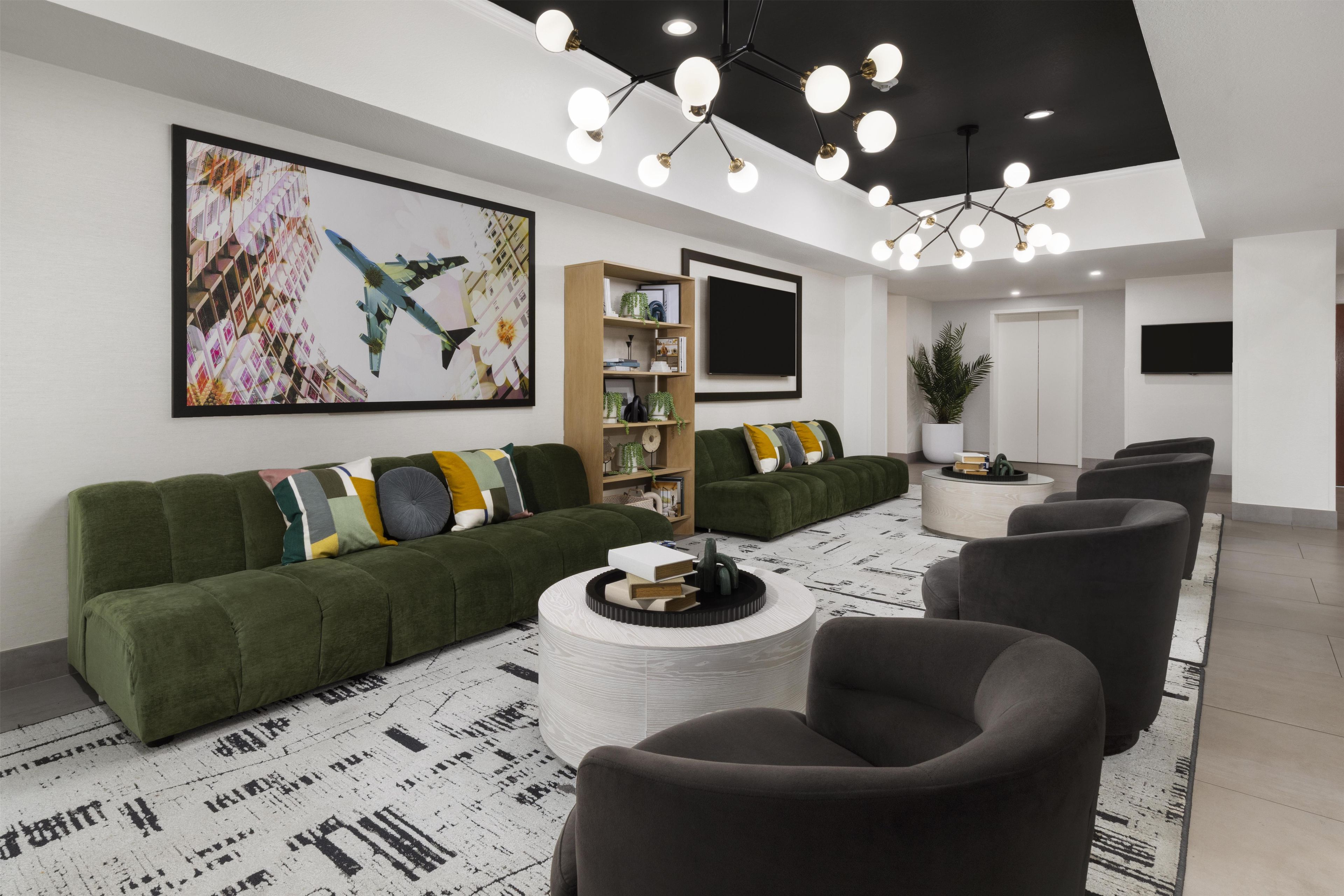 Un salon moderne avec un canapé vert, une table basse ronde et un grand tableau accroché au mur.
