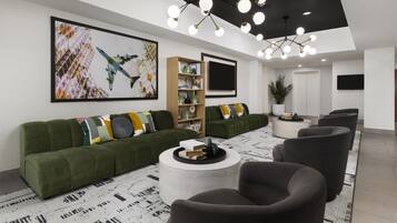 Un salon moderne avec un canapé vert, une table basse ronde et un grand tableau accroché au mur.