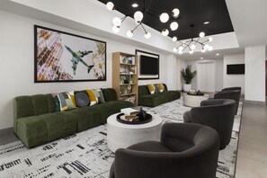 Un salon moderne avec un canapé vert, une table basse ronde et un grand tableau accroché au mur.