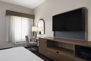 A hotel room with a bed, a desk with a lamp, a television, and a microwave. - Best Western Auburndale Inn & Suites (Auburndale)