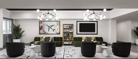 A modern living room with a sofa set, a coffee table, a bookshelf, and a flat-screen TV mounted on the wall.