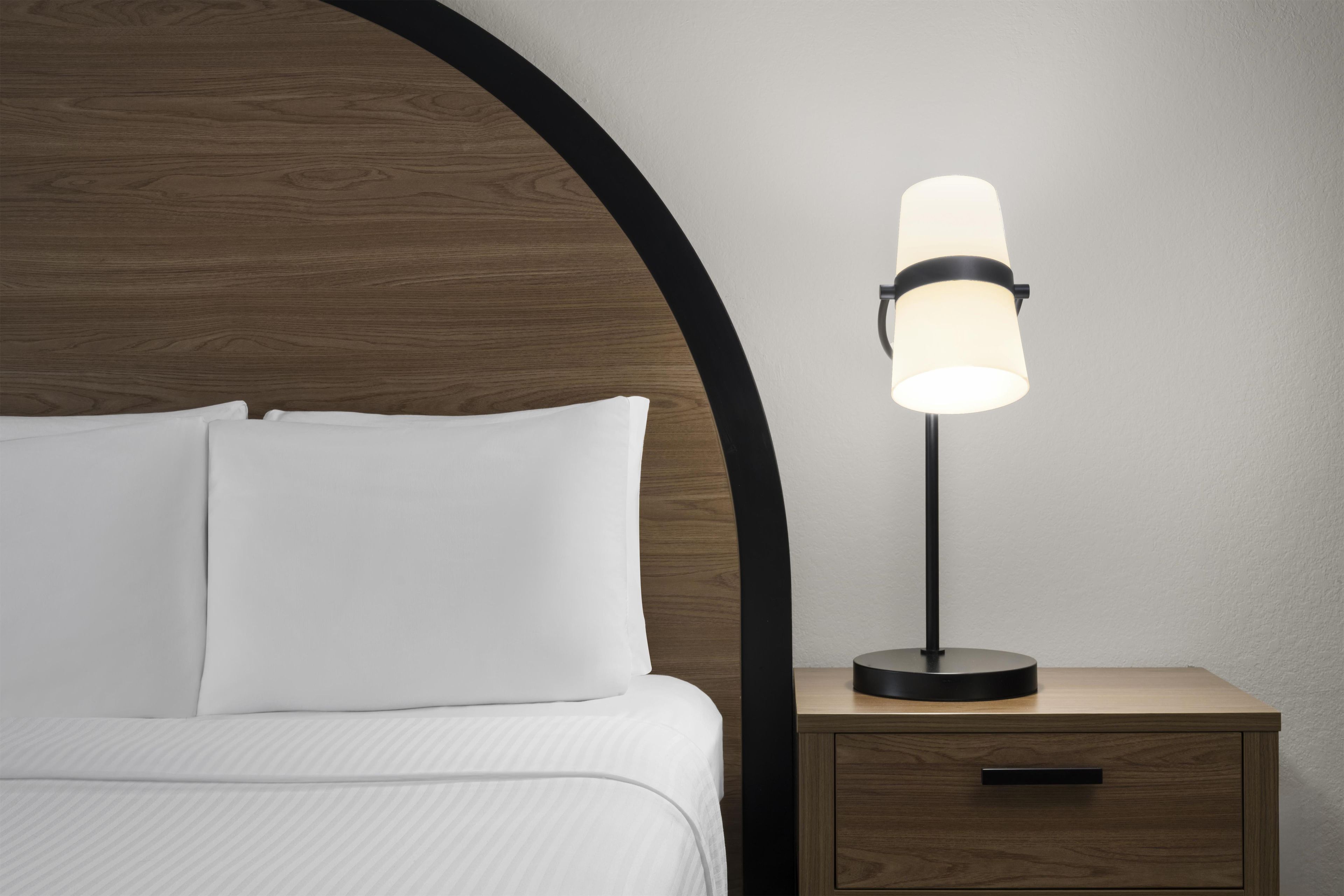 Ein Bett mit weißer Bettwäsche und ein Nachttisch mit einer Lampe.