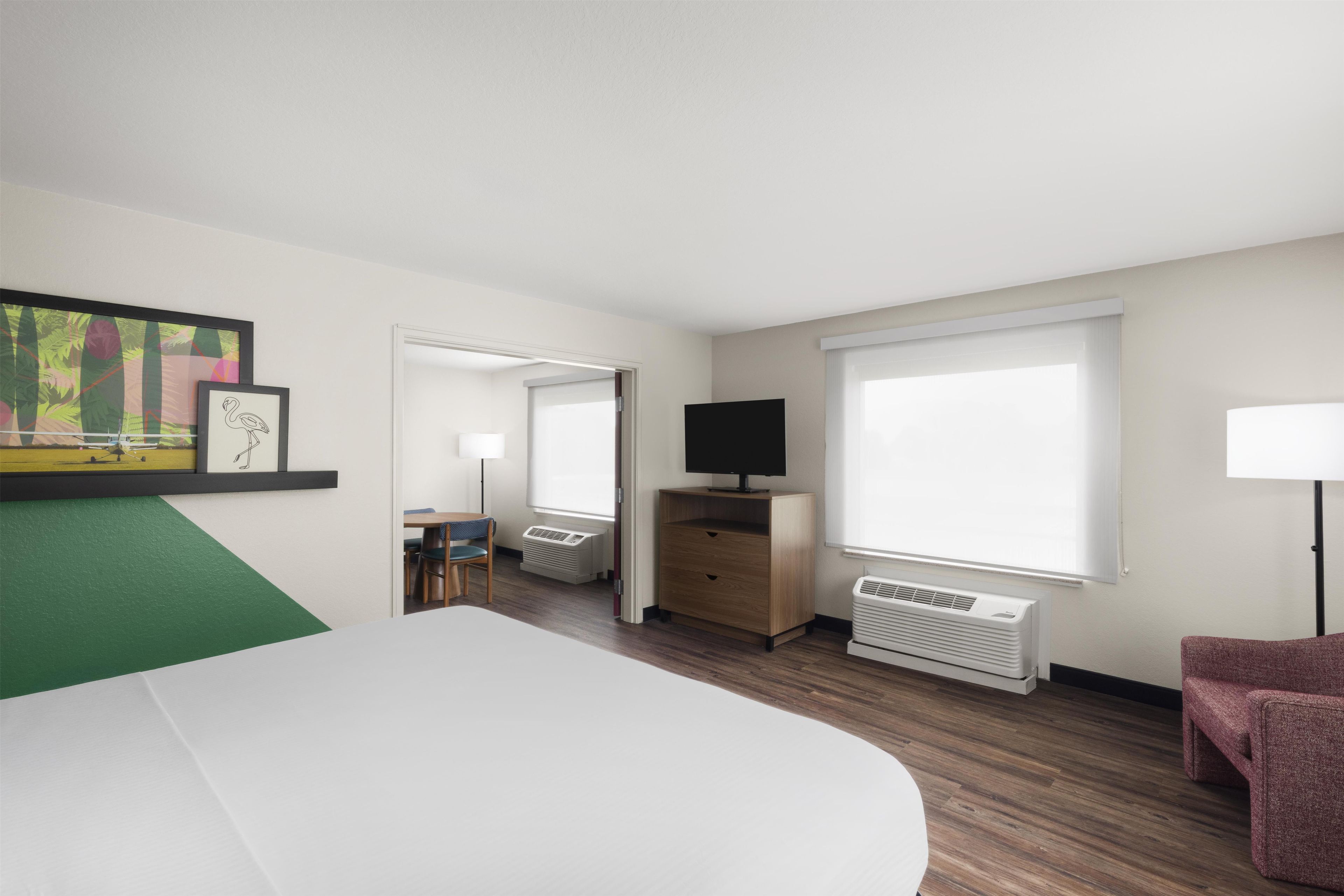 Una habitación de hotel con cama, televisión, escritorio, silla, lámpara y ventana.