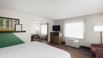 Una habitación de hotel con cama, televisión, escritorio, silla, lámpara y ventana.