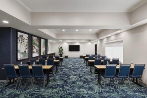 A conference room with a long table, chairs, a large screen, and framed artwork on the walls.