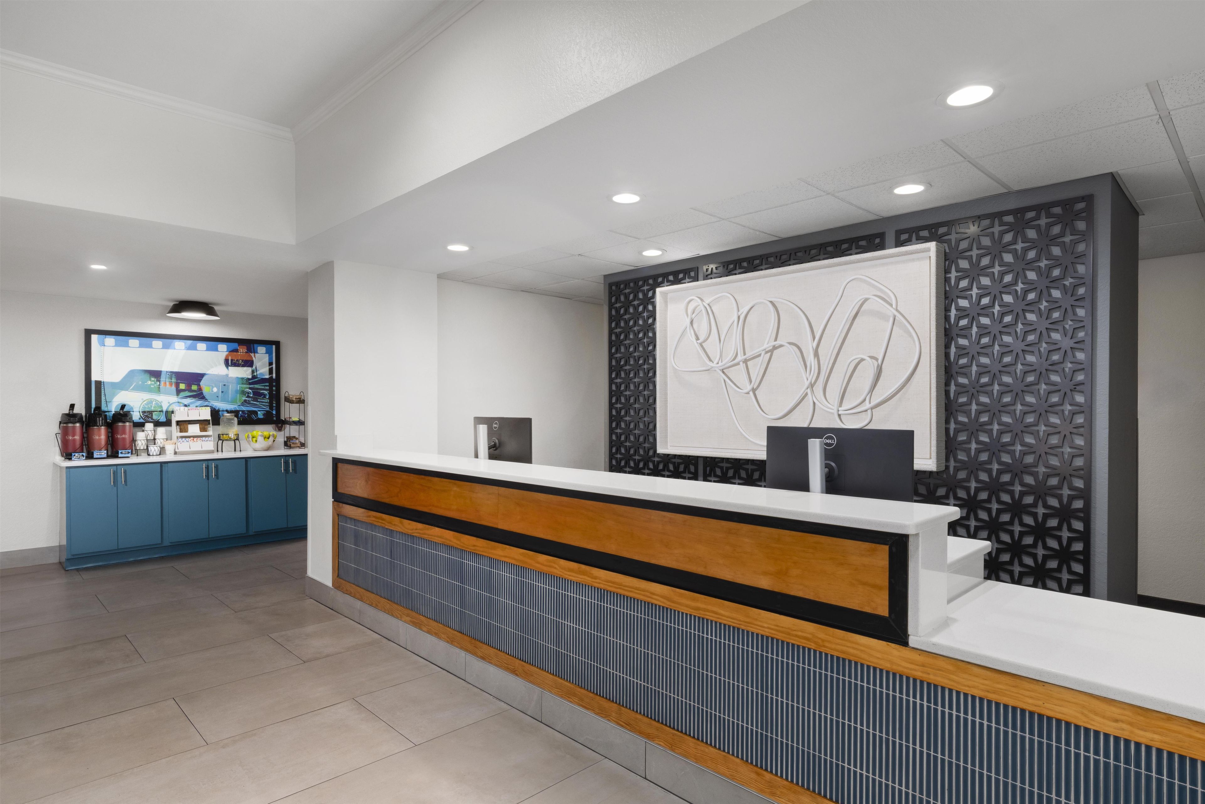 A reception area with a counter, a coffee machine, and a decorative wall.