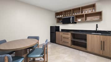 Cocina compacta con una mesa, sillas, microondas y refrigerador.