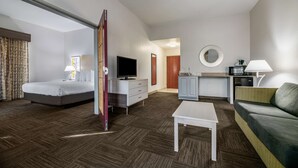 A hotel room with a bed, a television, a desk, a sofa, and a kitchen area. - Best Western Auburndale Inn & Suites (Auburndale)