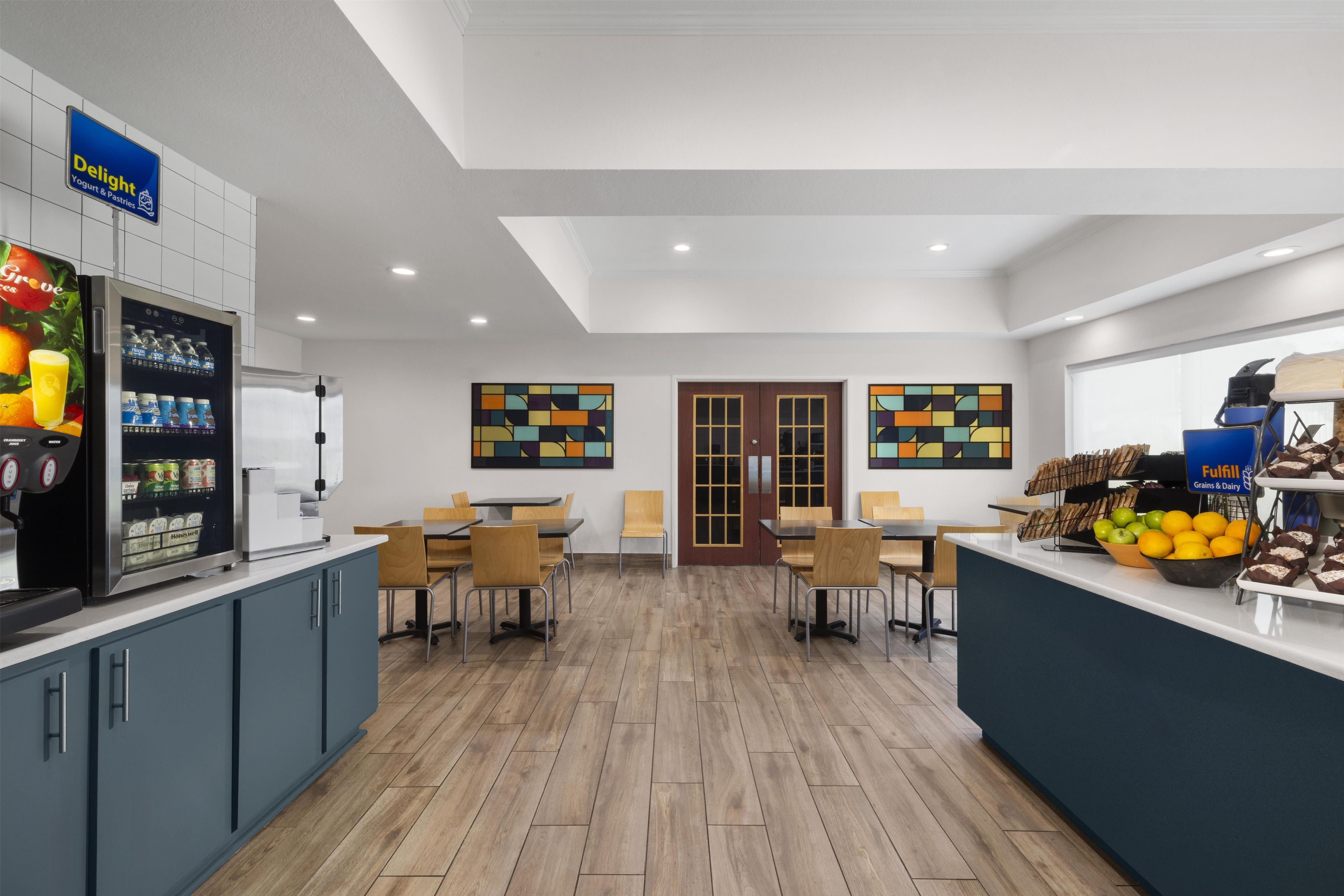 A modern kitchen area with a vending machine, seating area, and a counter with food items.