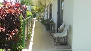 A covered outdoor area with a bench and potted plants. - Country Road Motel (Queenton)
