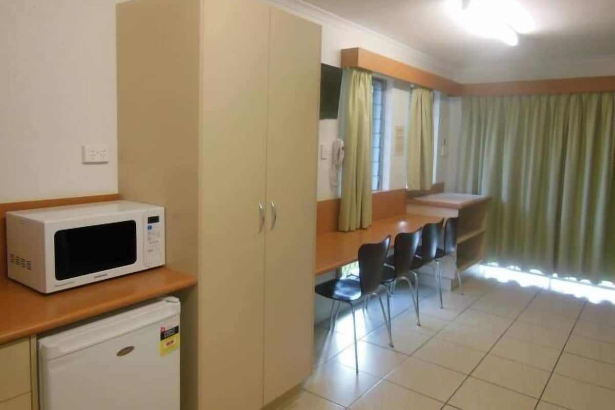 A kitchen with a microwave, a small refrigerator, and a dining area with chairs and a table.