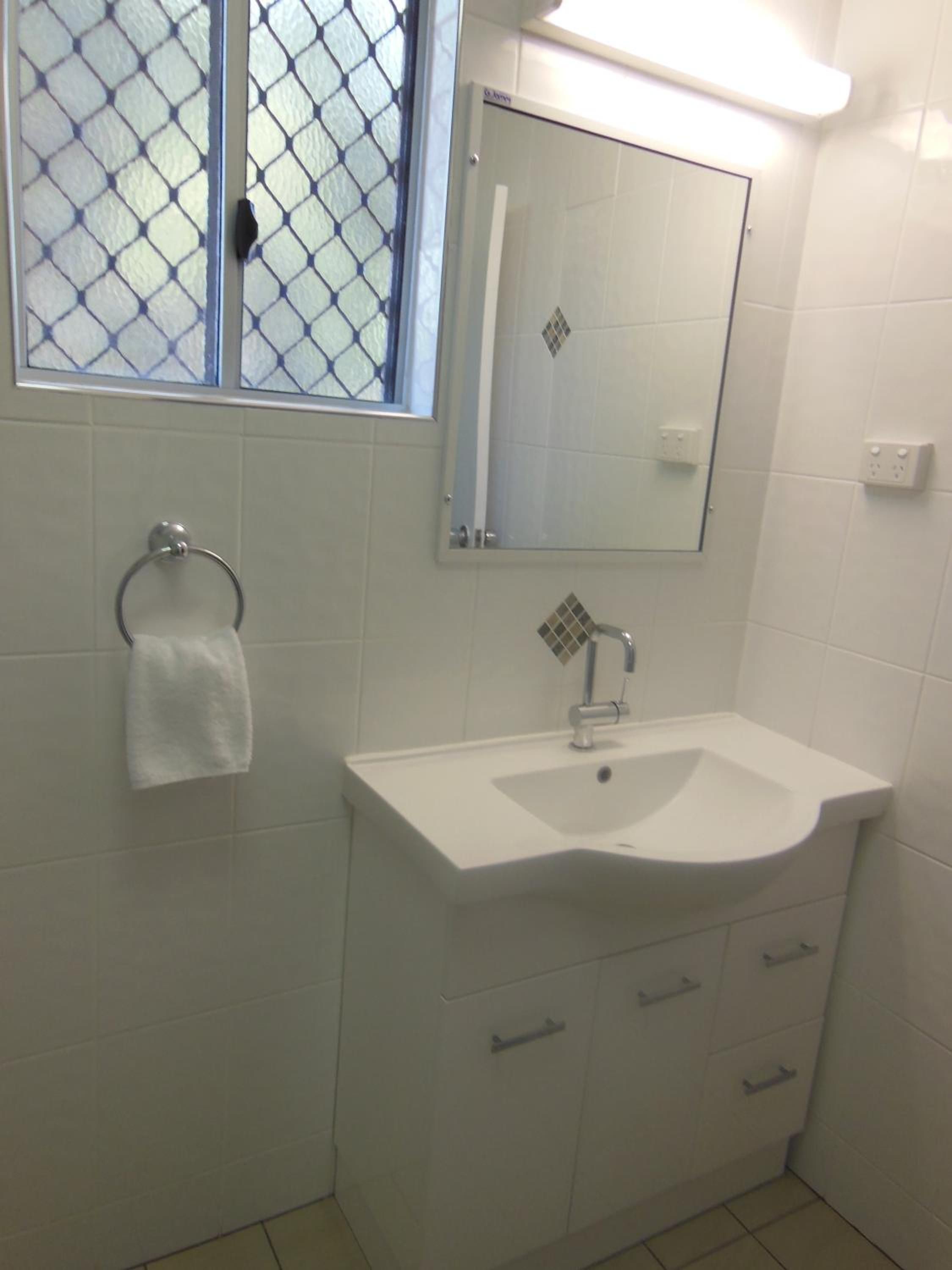 A bathroom with a white sink, a mirror, and a towel rack.