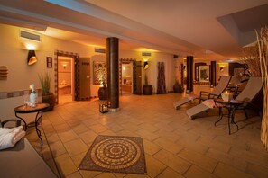 A spacious lobby with a tiled floor, a central column, and a seating area with lounge chairs and a small table.