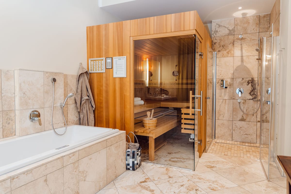 Une salle de bain moderne avec un sauna en bois, une douche à parois de verre et une baignoire.